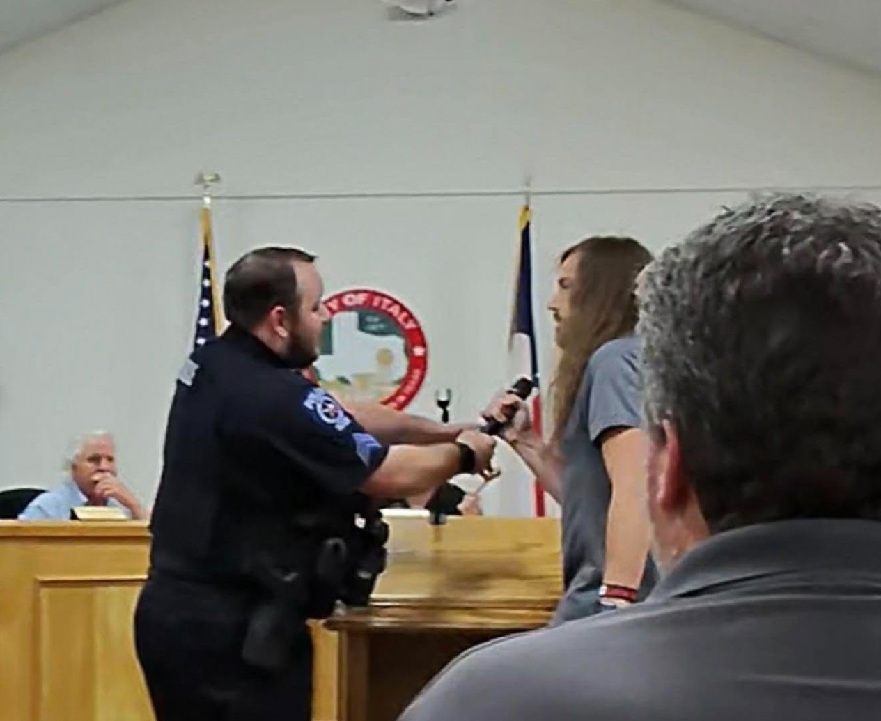 An Italy police officer taking a microphone from Ron Helms at an Italy City Council meeting