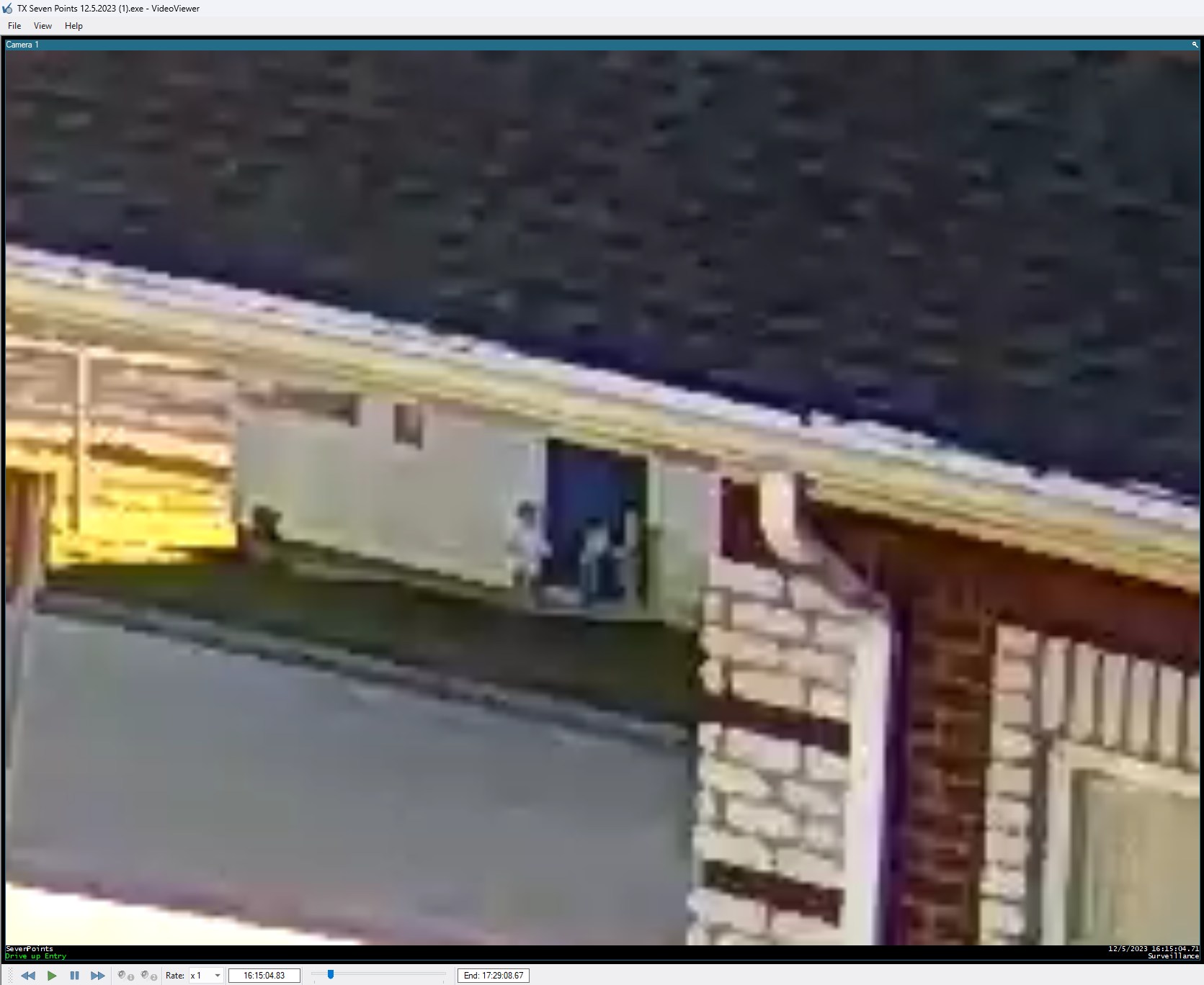 The Simmons Bank camera at 4:15 p.m. on December 5, 2023, zoomed in on the infant room's blue exit door across the parking lot. Three toddlers are outside the door. No adult is in view.