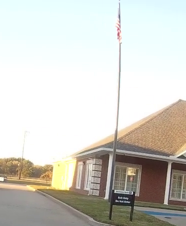 The flag on Simmons Bank's flagpole at 4:45 p.m. on December 5, 2023, on the responding officer's body camera. I cropped the frame to the pole and the bank.